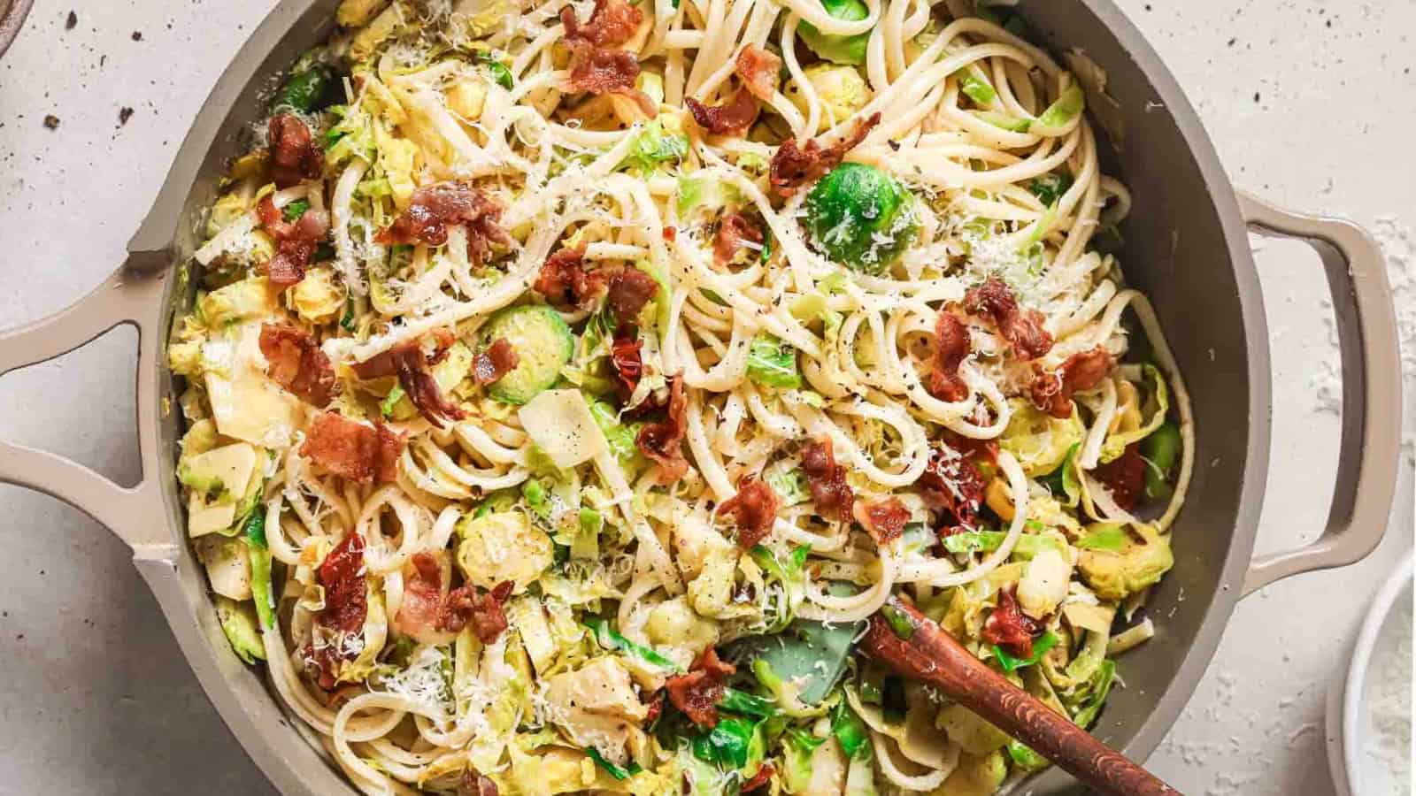 A bowl of pasta with bacon and brussels sprouts.