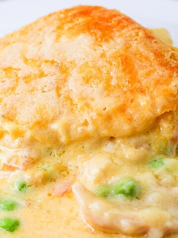 A serving of creamy chicken pot pie with peas on a white plate.
