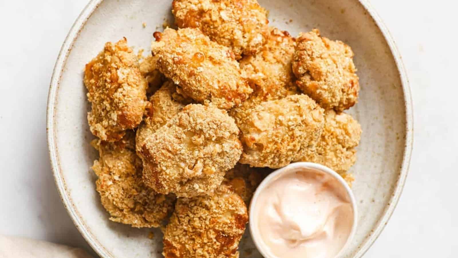 Keto chicken nuggets on a plate with a cup of dipping sauce.
