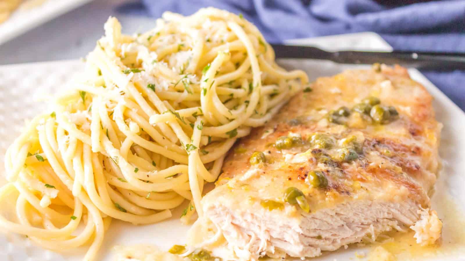 Chicken breast cut with pasta in the background.