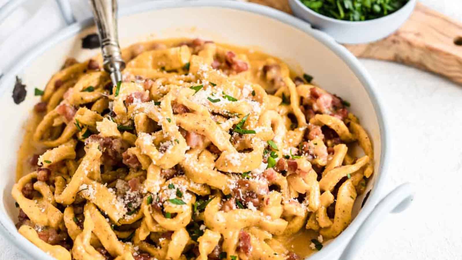 Pasta Carbonara inside a bowl with herbs and bacon.