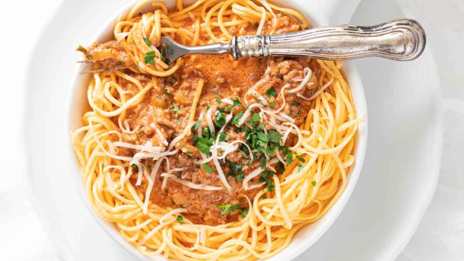 Low Carb Spaghetti Bolognese in a grey bowl with extra sauce on the side.