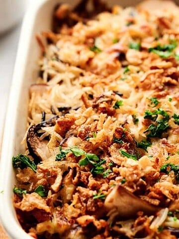 Golden baked casserole topped with crispy onions and fresh herbs in a white dish.