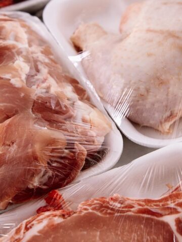 Various cuts of raw meat packaged in white foam trays and wrapped in plastic wrap.