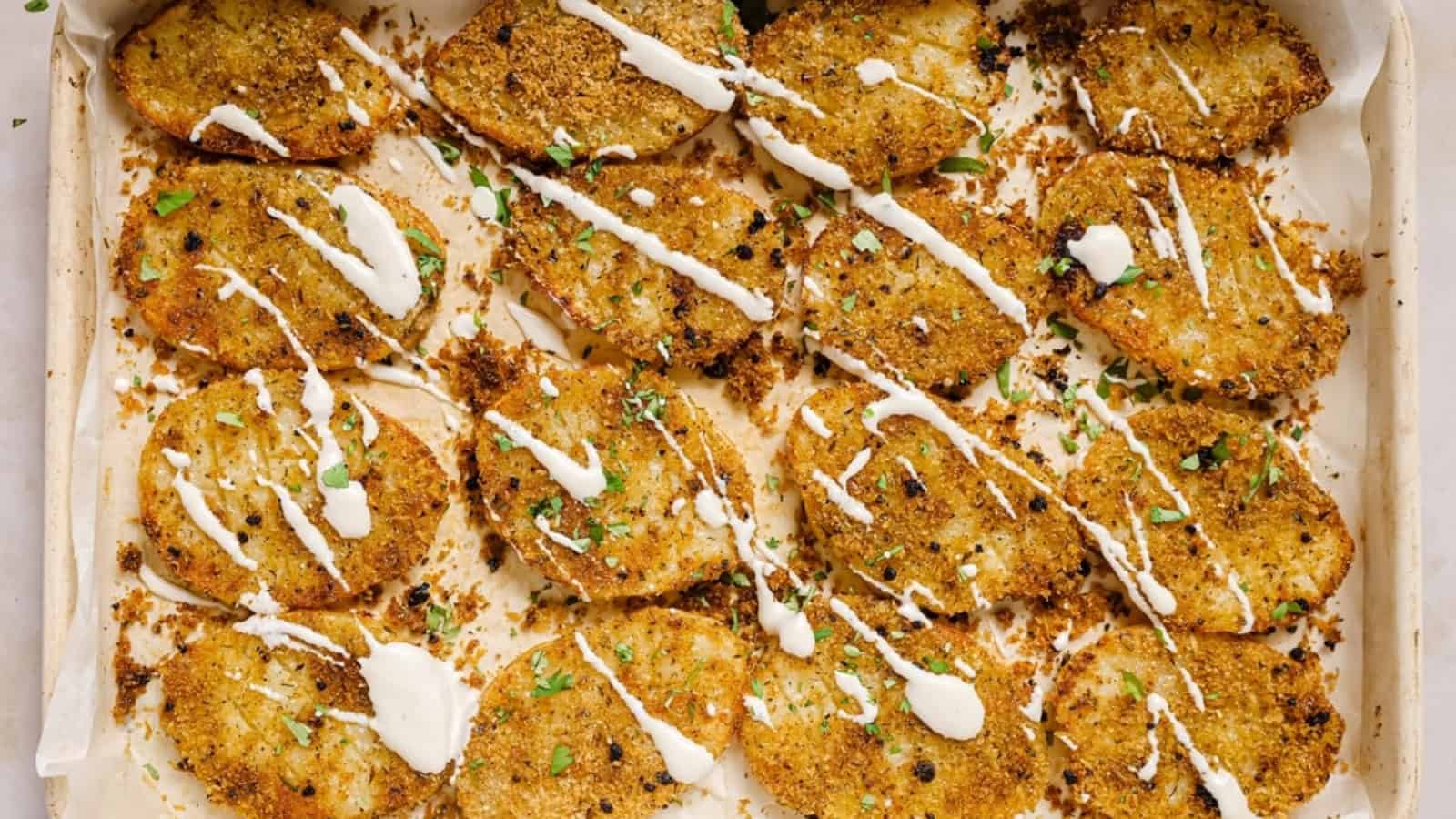 A baking sheet with garnished parmesan crusted potatoes on it.