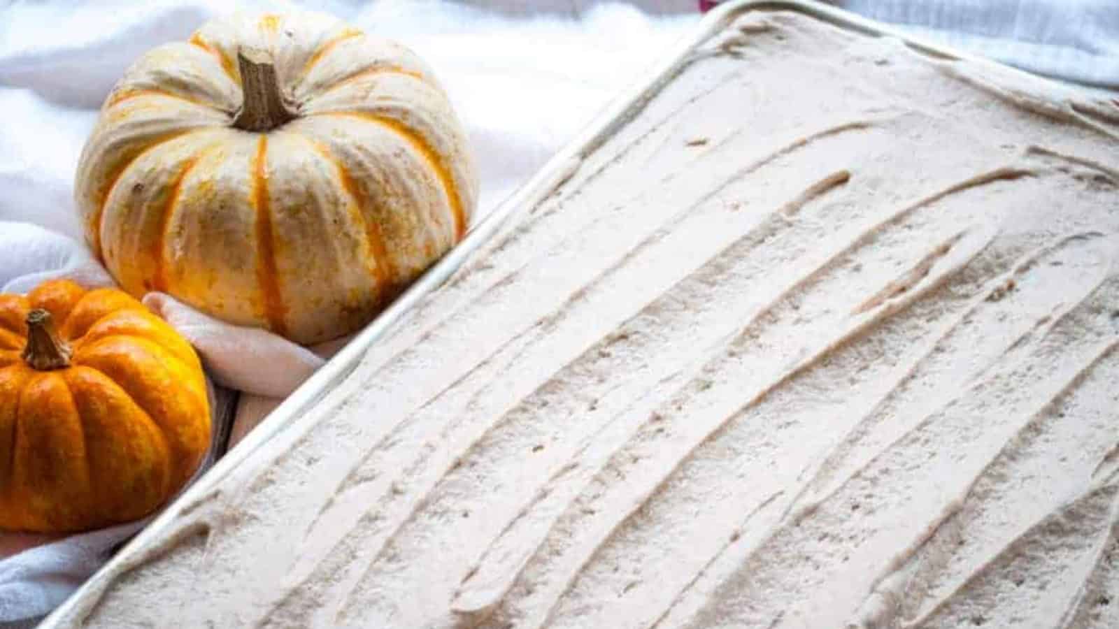 Pumpkin ice cream in a pan surrounded by pumpkins.