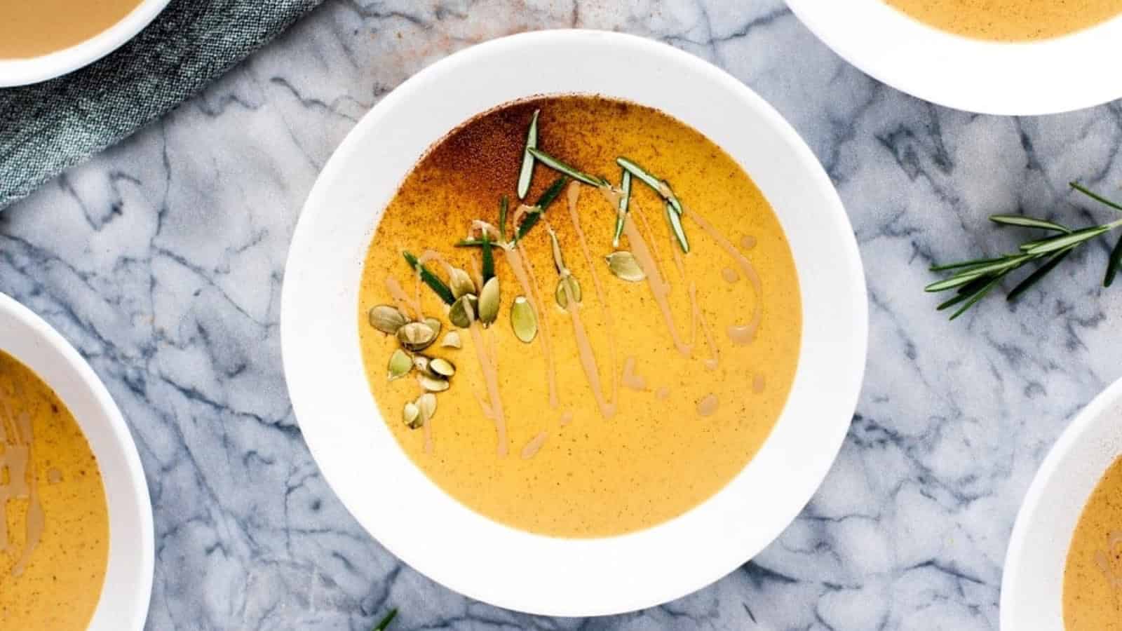 Bowls of pumpkin soup with sprigs of rosemary.