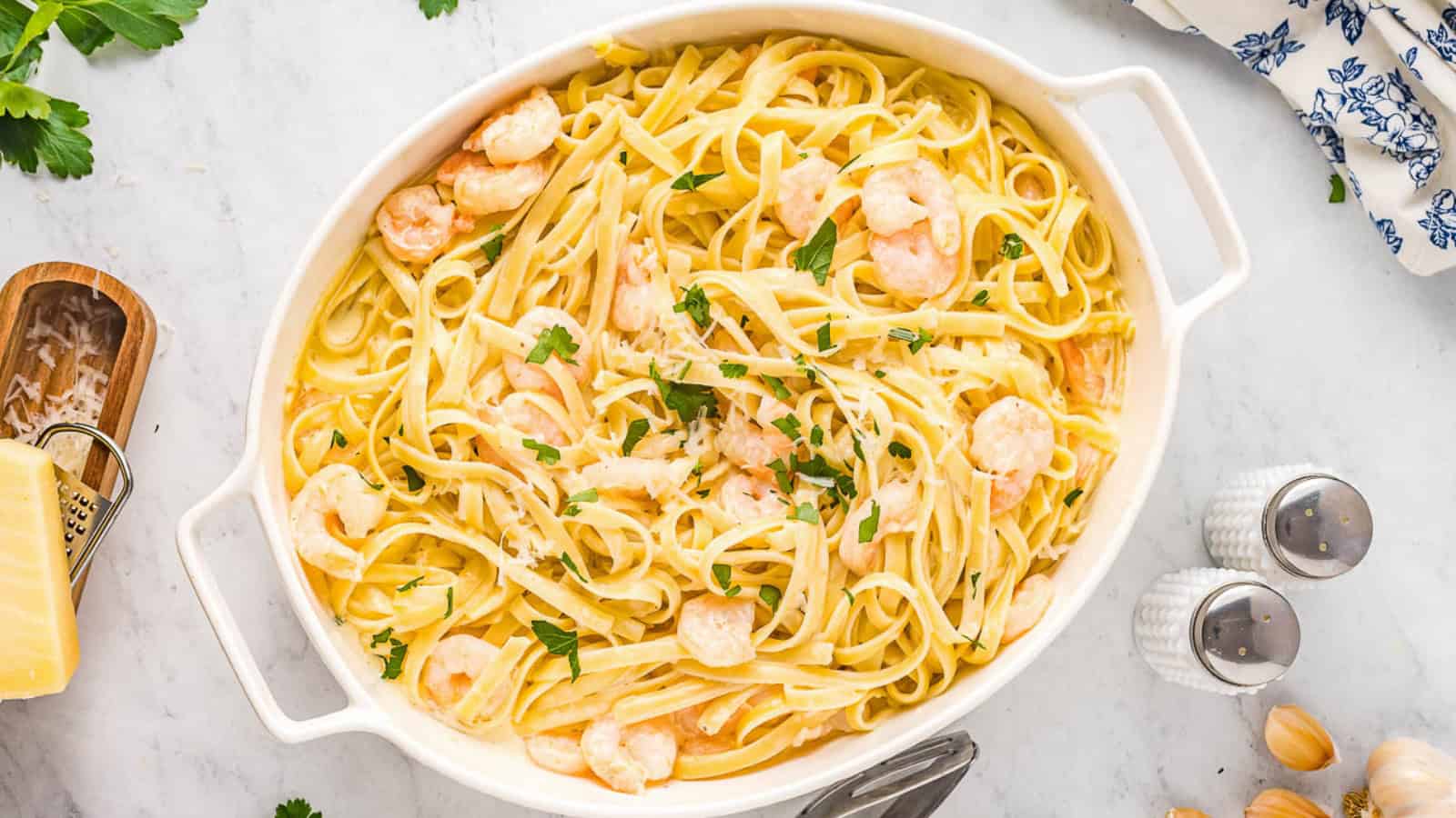 Shrimp and fettuccine pasta in a large glass bowl.