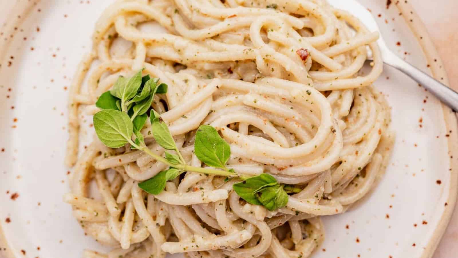 A plate of creamy pasta garnished with fresh herbs, served on a white dish with a fork.