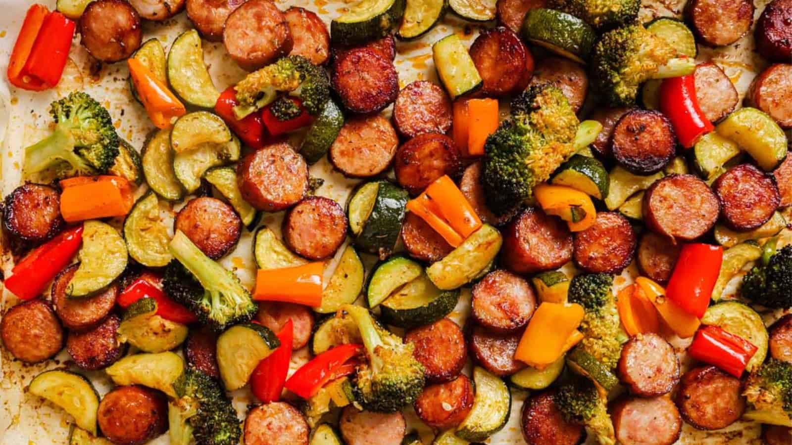 Sausage and veggies sheet pan dinner with a spoon.