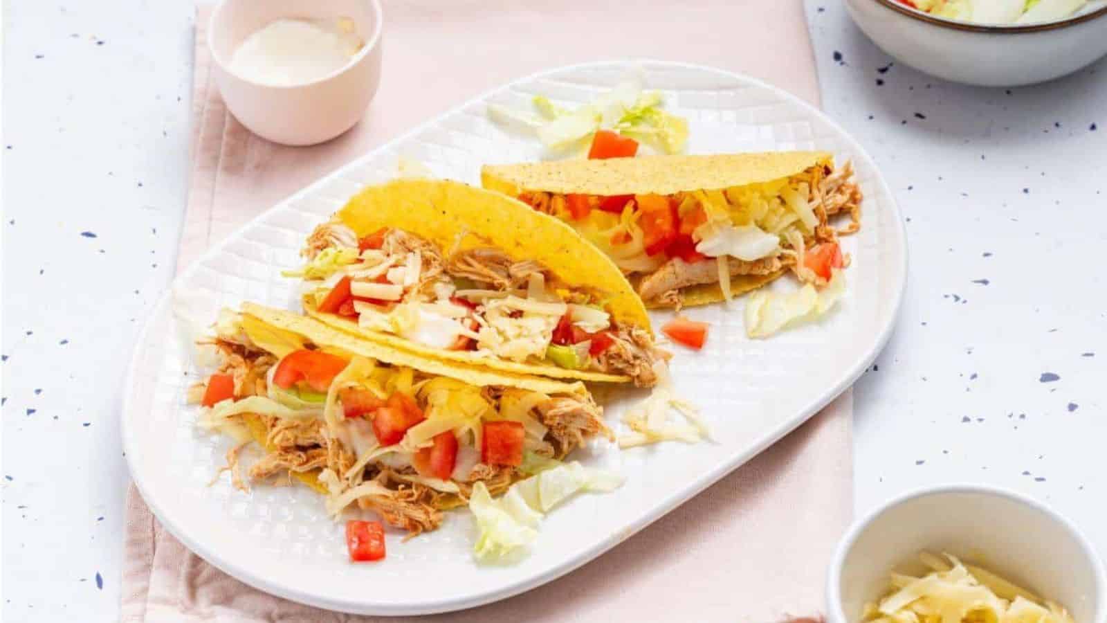 Two tacos on a plate with a bowl of guacamole.