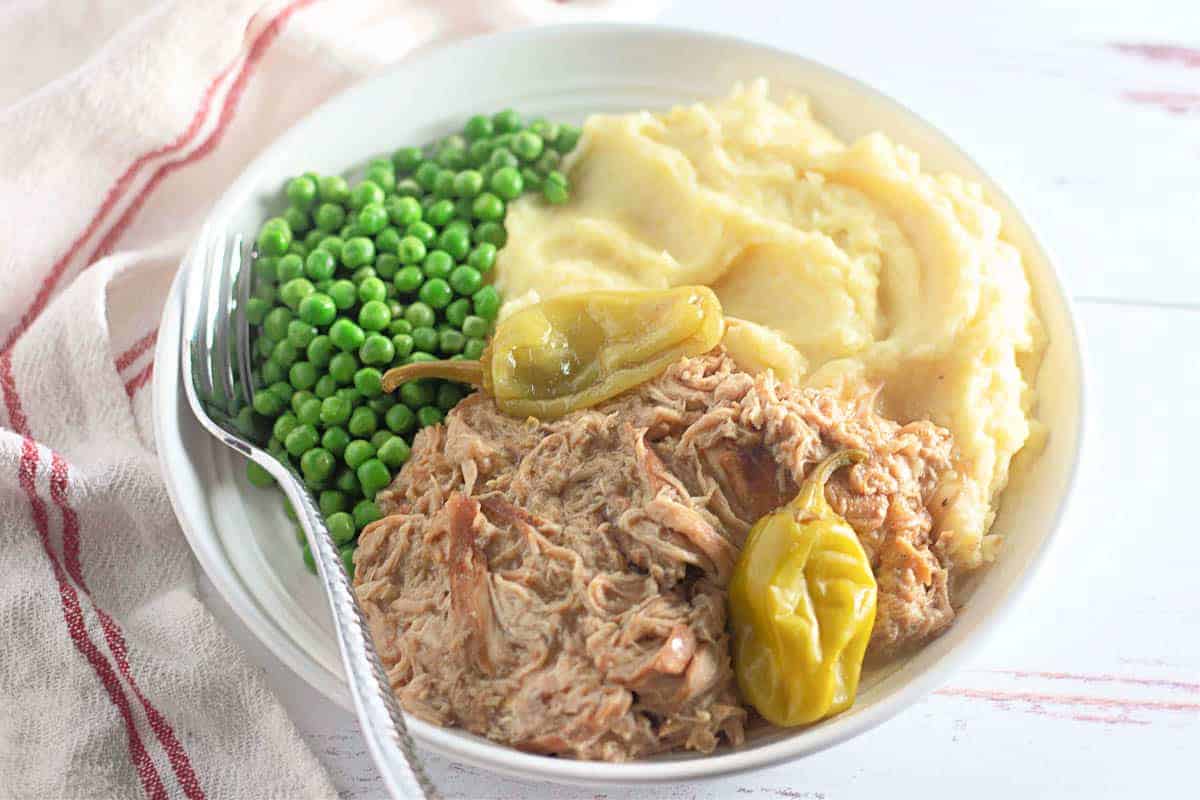 A dinner plate with chicken and peas. 
