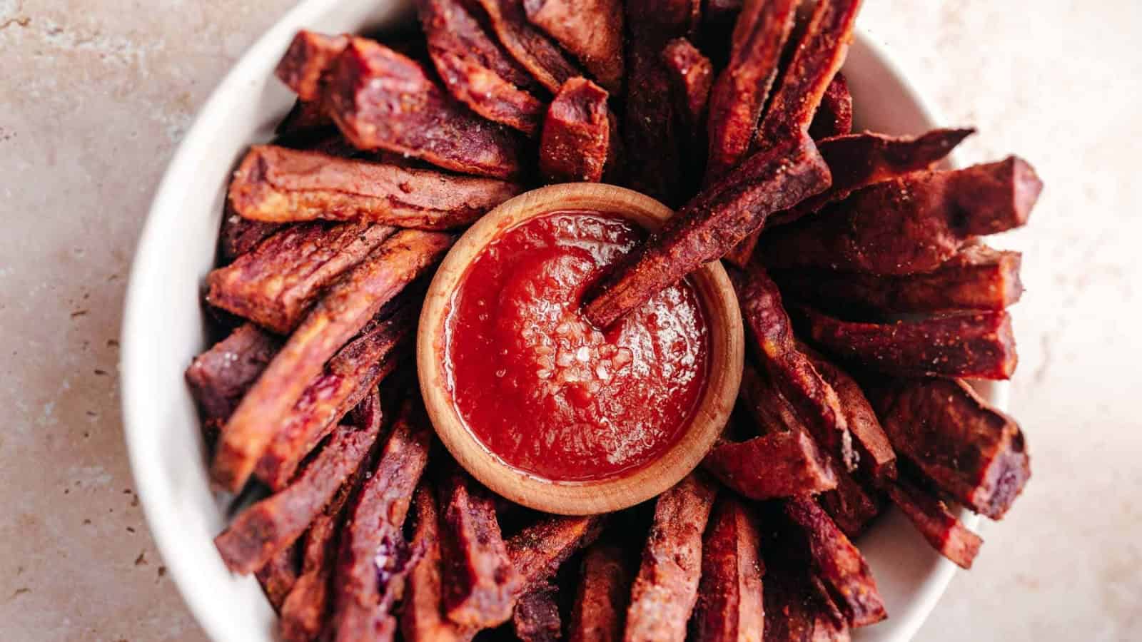 Sweet potato fries arranged in a bowl around a small dish of ketchup for dipping.