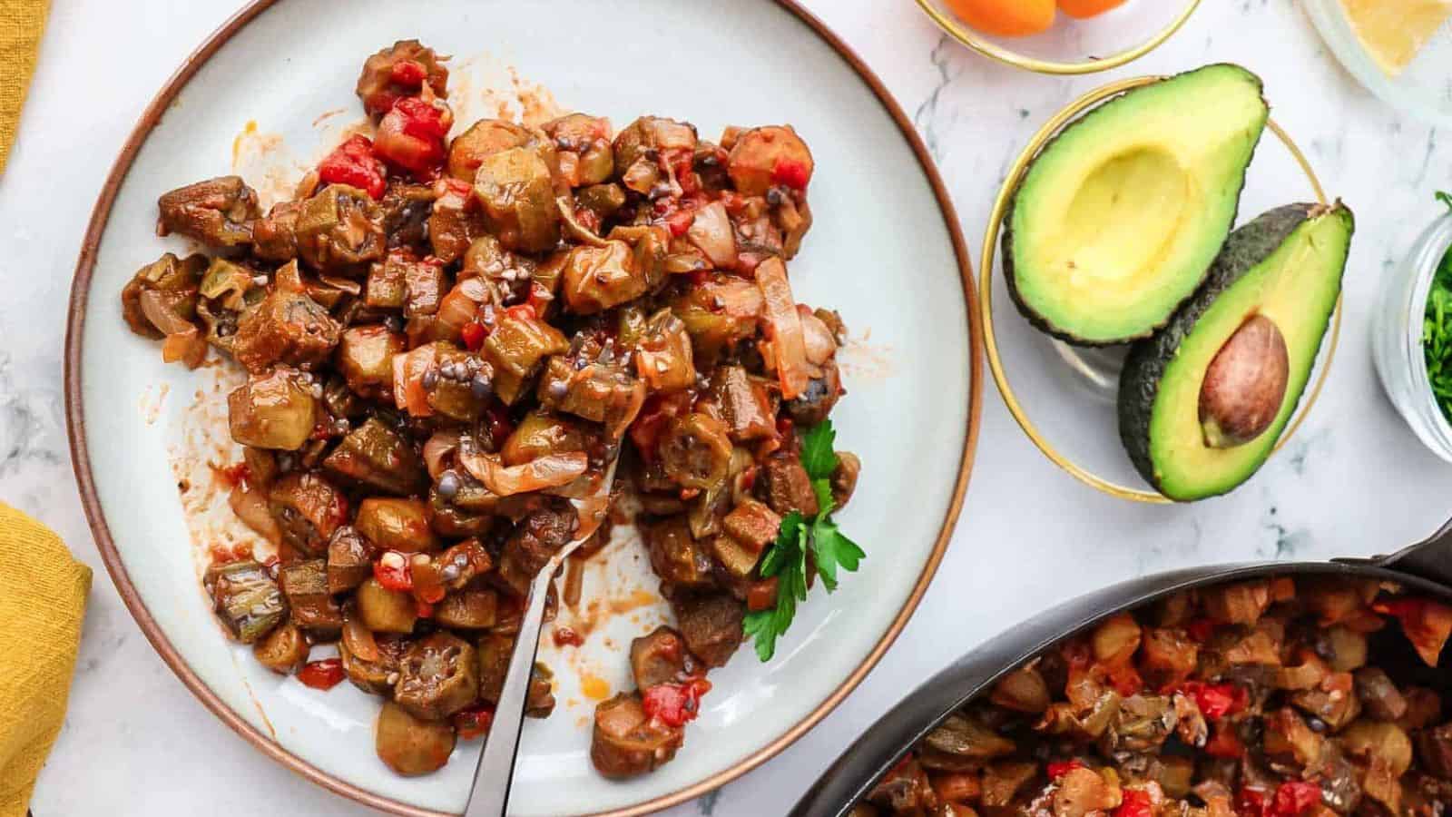 Stewed okra and tomatoes on a plate with parsley garnish.
