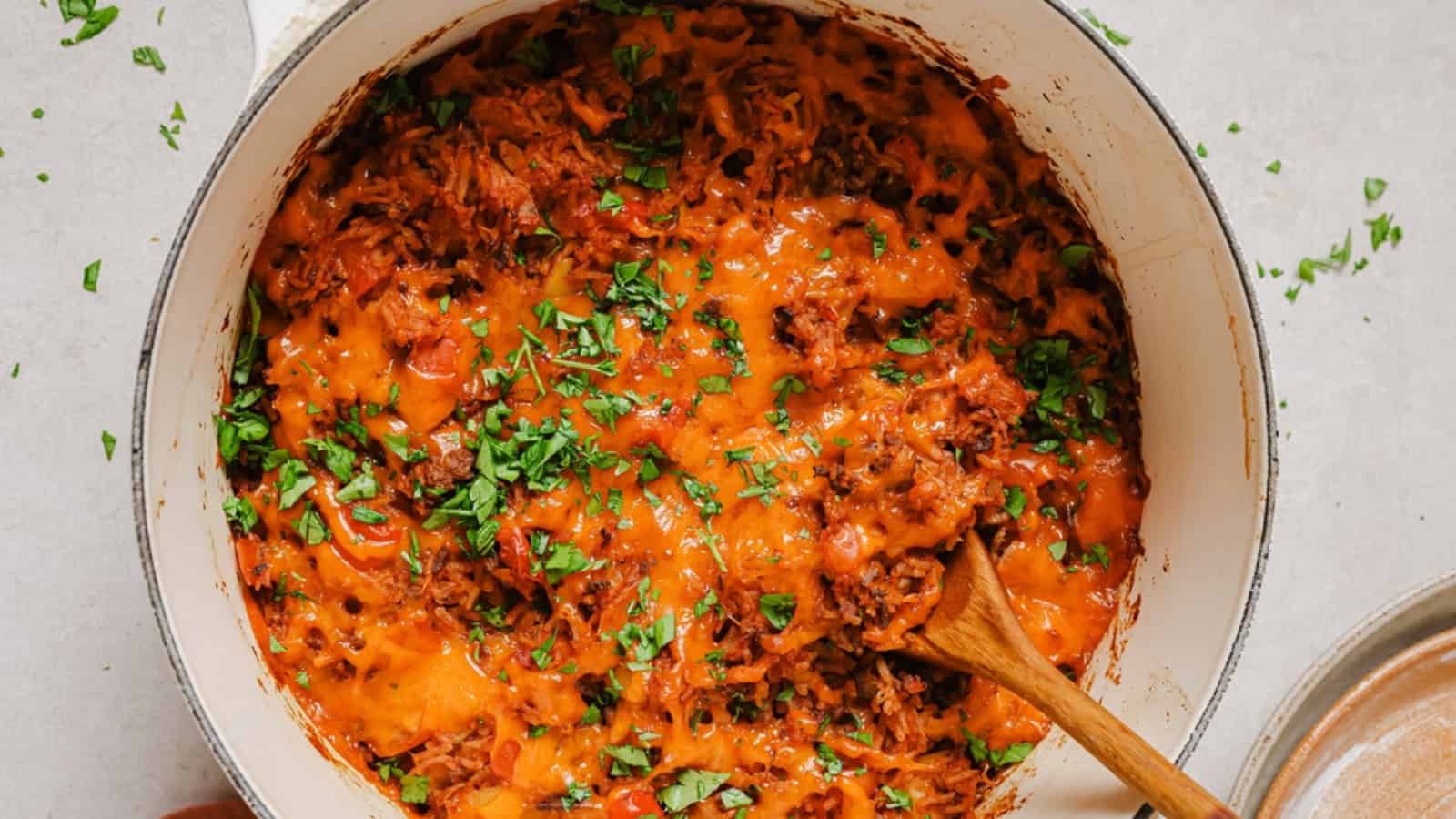 Stuffed bell pepper casserole in a pan with a wooden spoon.