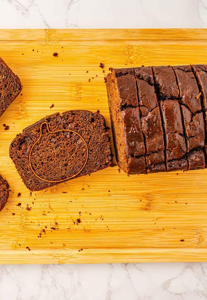 Sliced Pumpkin Banana Bread loaf on a wooden board, with a festive pumpkin-shaped outline on one slice&mdash;perfect for Halloween.