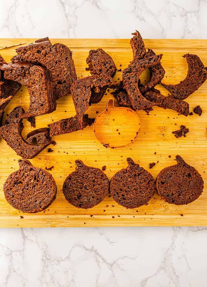 A wooden board with chocolate cake scraps and round pumpkin-shaped cake cutouts, perfect for a Halloween treat or pairing with Pumpkin Banana Bread.