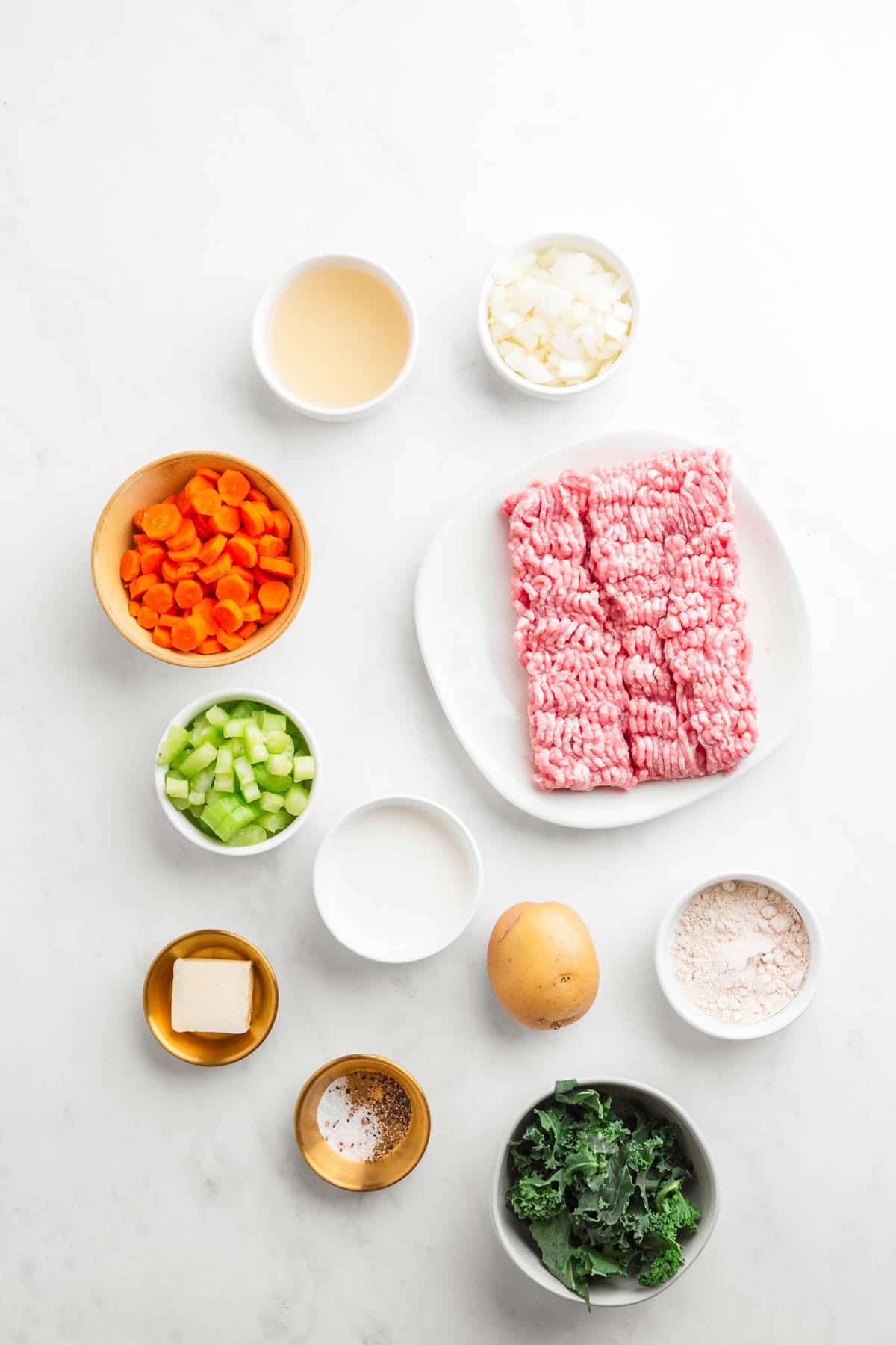 Ingredients for a hearty Potato Soup recipe: ground meat, carrot, celery, onion, potato, kale, butter, flour, milk, broth, and spices&mdash;perfect for creating a comforting Tuscan Sausage-inspired dish.