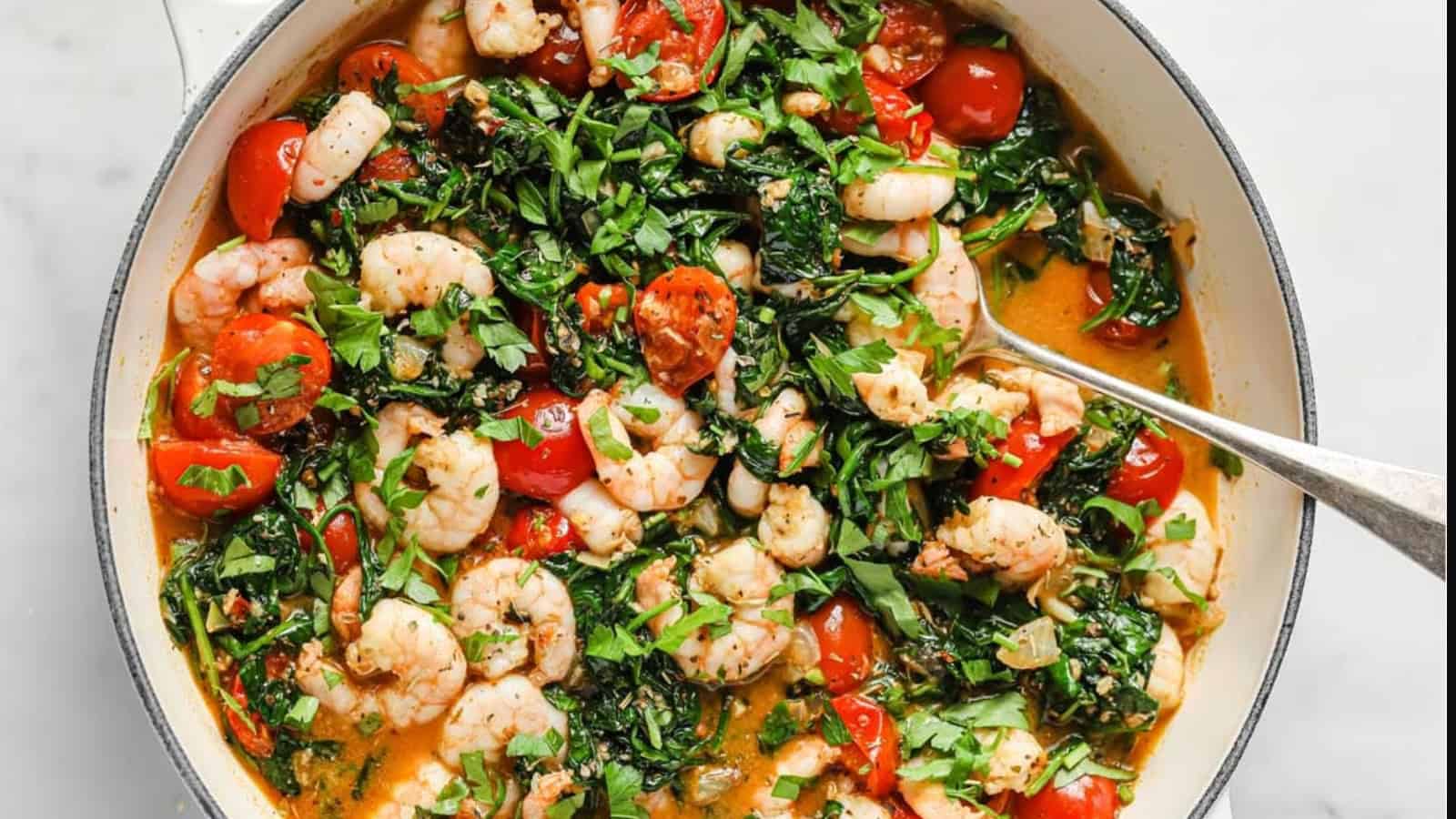 Tuscan garlic shrimp and spinach with tomatoes in a pan.