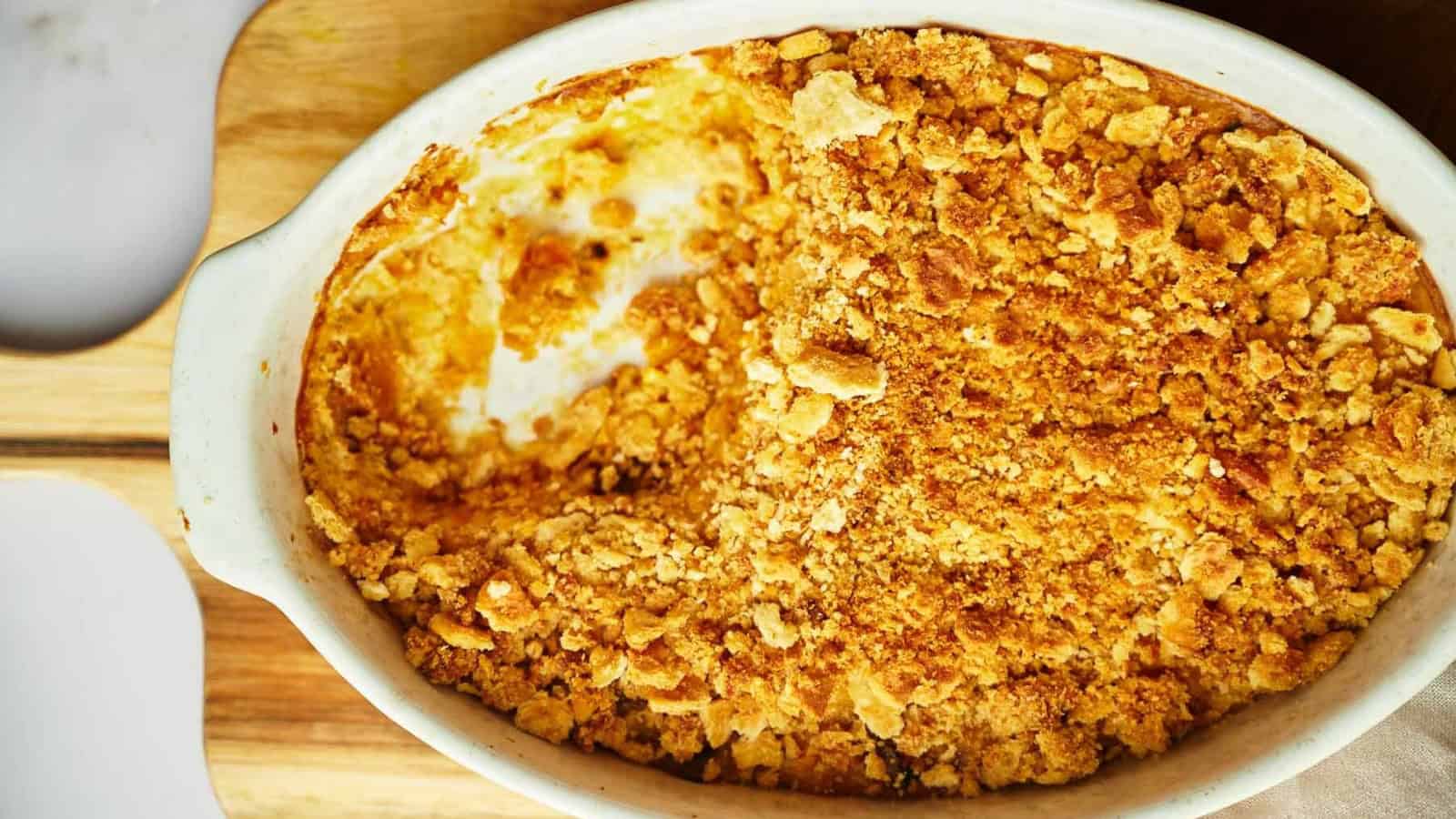 Squash casserole being served with a wooden serving spoon.