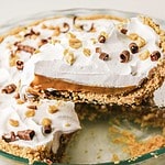 A caramel pie featuring whipped cream, luscious caramel filling, and chocolate curls in a glass pie dish—perfect for trying a new recipe at home.