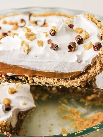 A caramel pie featuring whipped cream, luscious caramel filling, and chocolate curls in a glass pie dish—perfect for trying a new recipe at home.