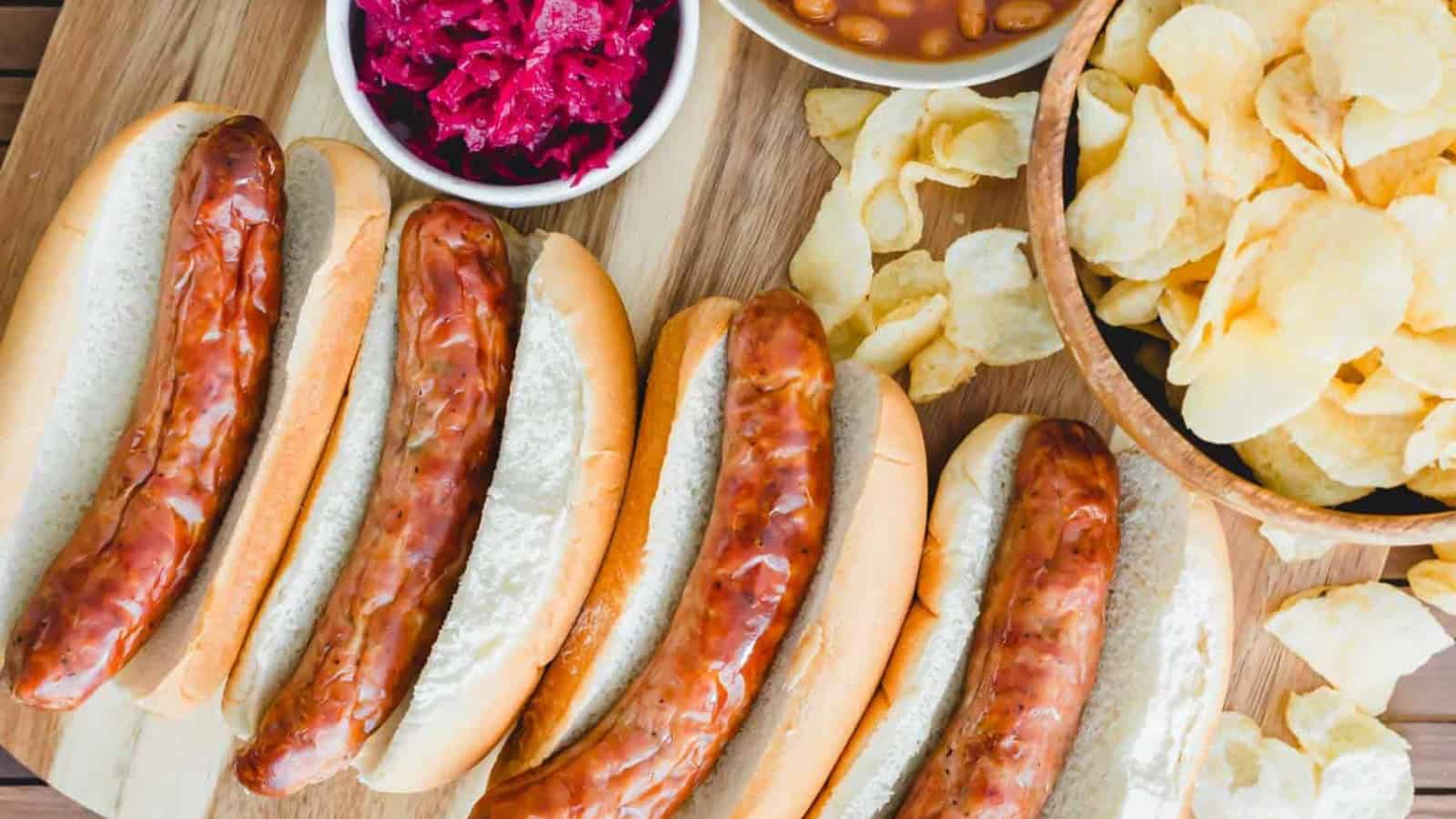 Air fryer brats on buns with potato chips on the side.