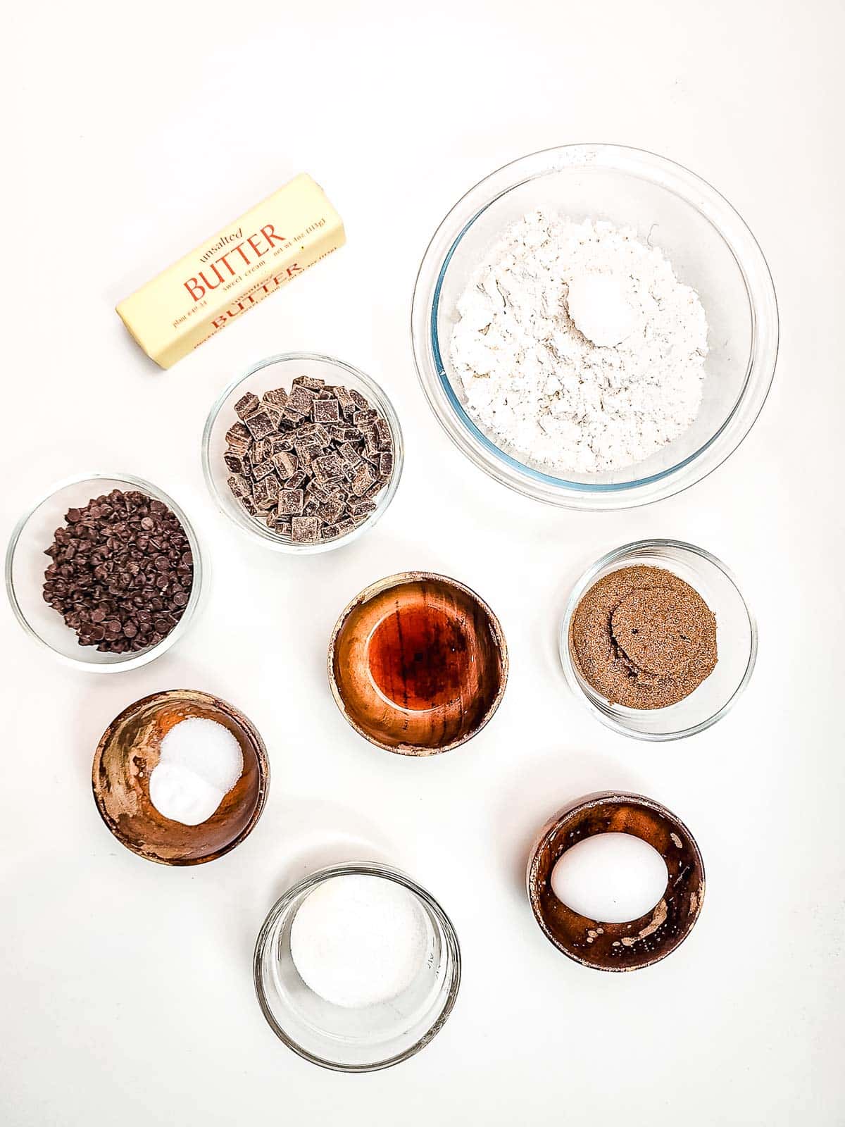 Baking ingredients arranged on a white surface: butter, flour, sugars, egg, chocolate, vanilla, salt, and baking soda&mdash;everything you need to make delicious Air Fryer Cookies.