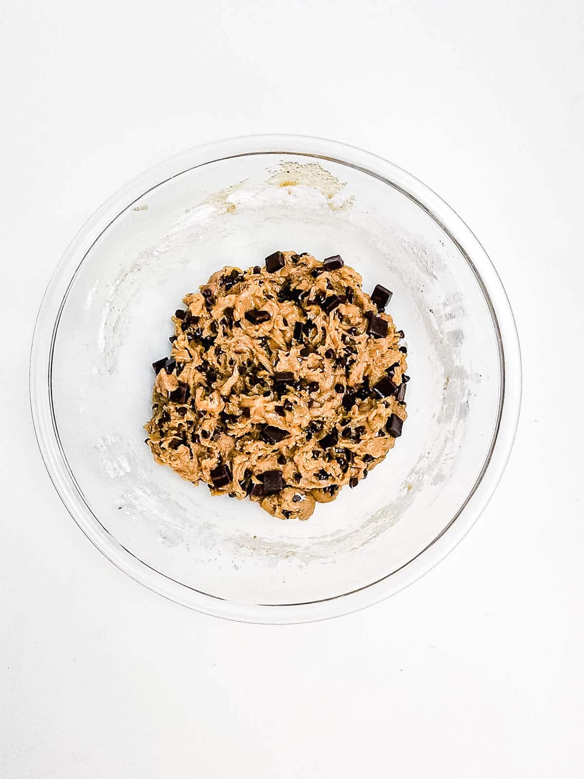Glass bowl with chocolate chip cookie dough on a white background, perfect for baking delicious Chocolate Chunk Cookies in your Air Fryer.