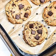 Chocolate Chunk Cookies with chunky chocolate pieces rest on parchment paper in an air fryer basket, perfectly baked as delicious air fryer cookies.