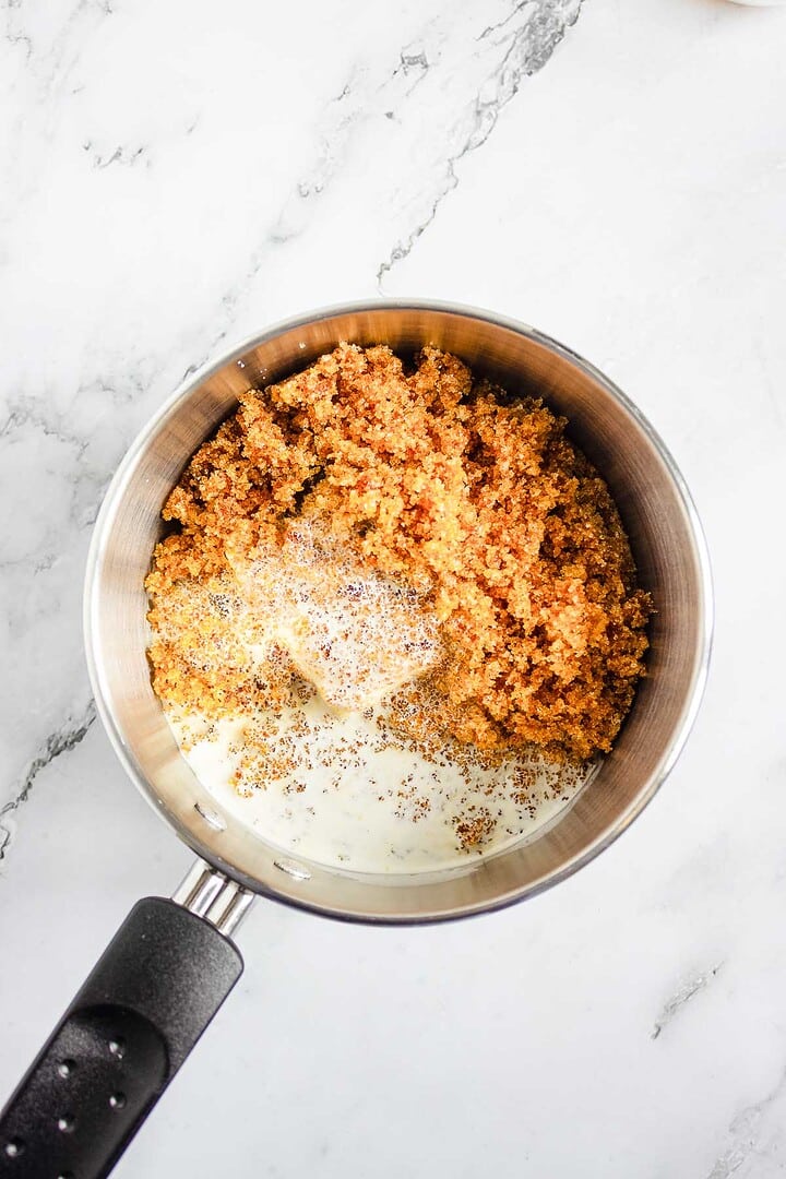 A saucepan with brown sugar and cream mixture on a marble countertop, ready to be mixed for rich caramel sauce&mdash;perfect for pairing with air fryer churro donut holes.