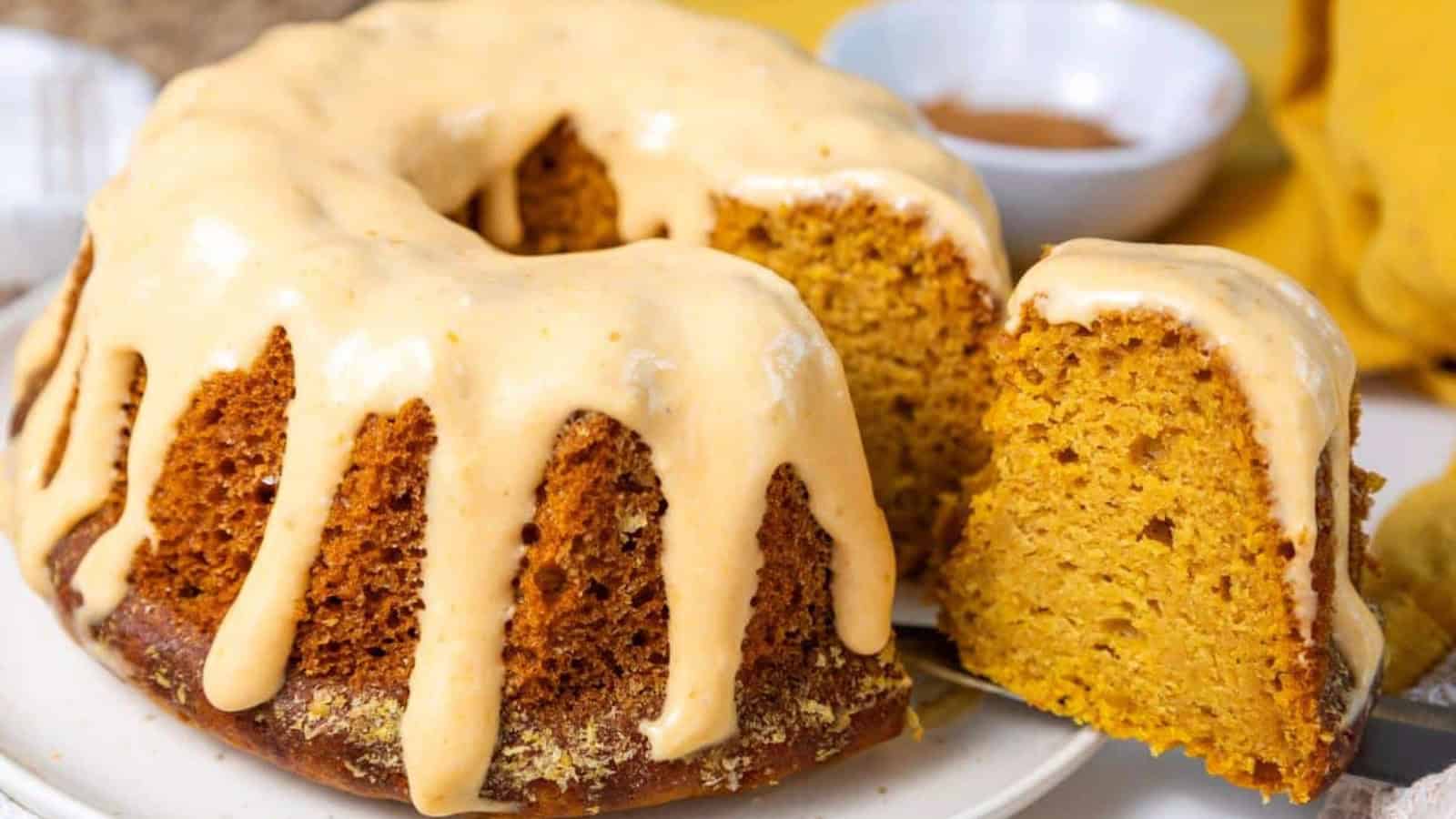 A pumpkin bundt cake with vanilla glaze on a white plate.