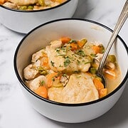 Two bowls of hearty Chicken and Dumplings stew with carrots and peas, garnished with chopped parsley—a perfect easy dinner for any night.