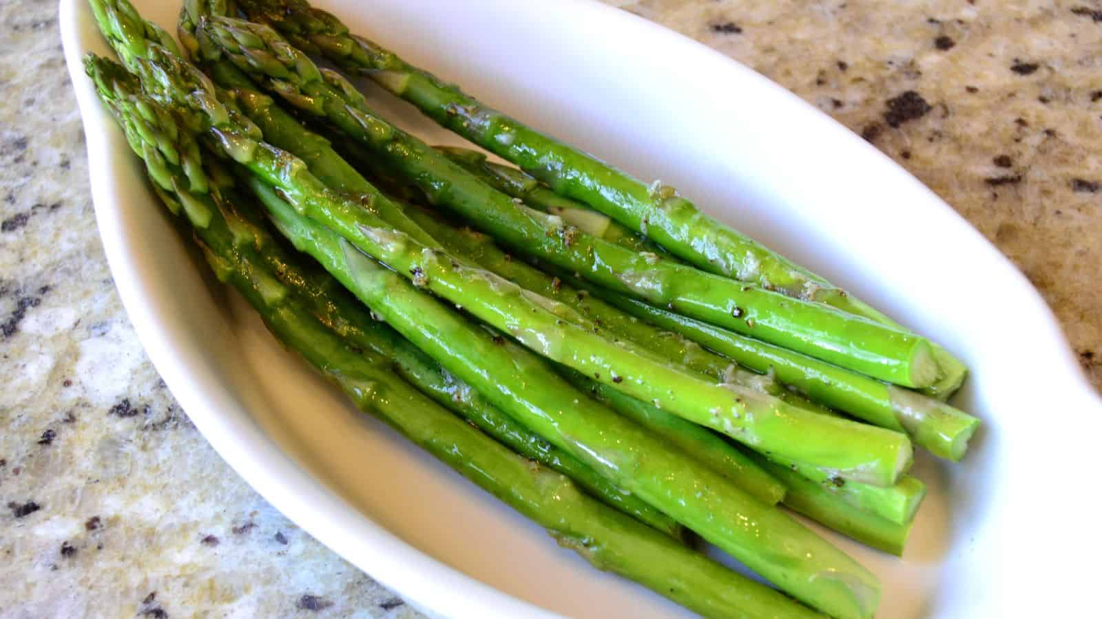 Cooked asparagus in a white bowl.