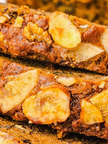 Close-up of sliced banana bread topped with walnuts and banana chips.