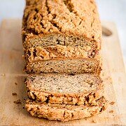 Sliced loaf of banana bread with streusel topping on a wooden cutting board.