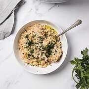 Bowl of creamy Crockpot chicken and rice garnished with herbs, next to a slow cooker and a sprig of parsley—a cozy classic for fans of easy crockpot recipes.