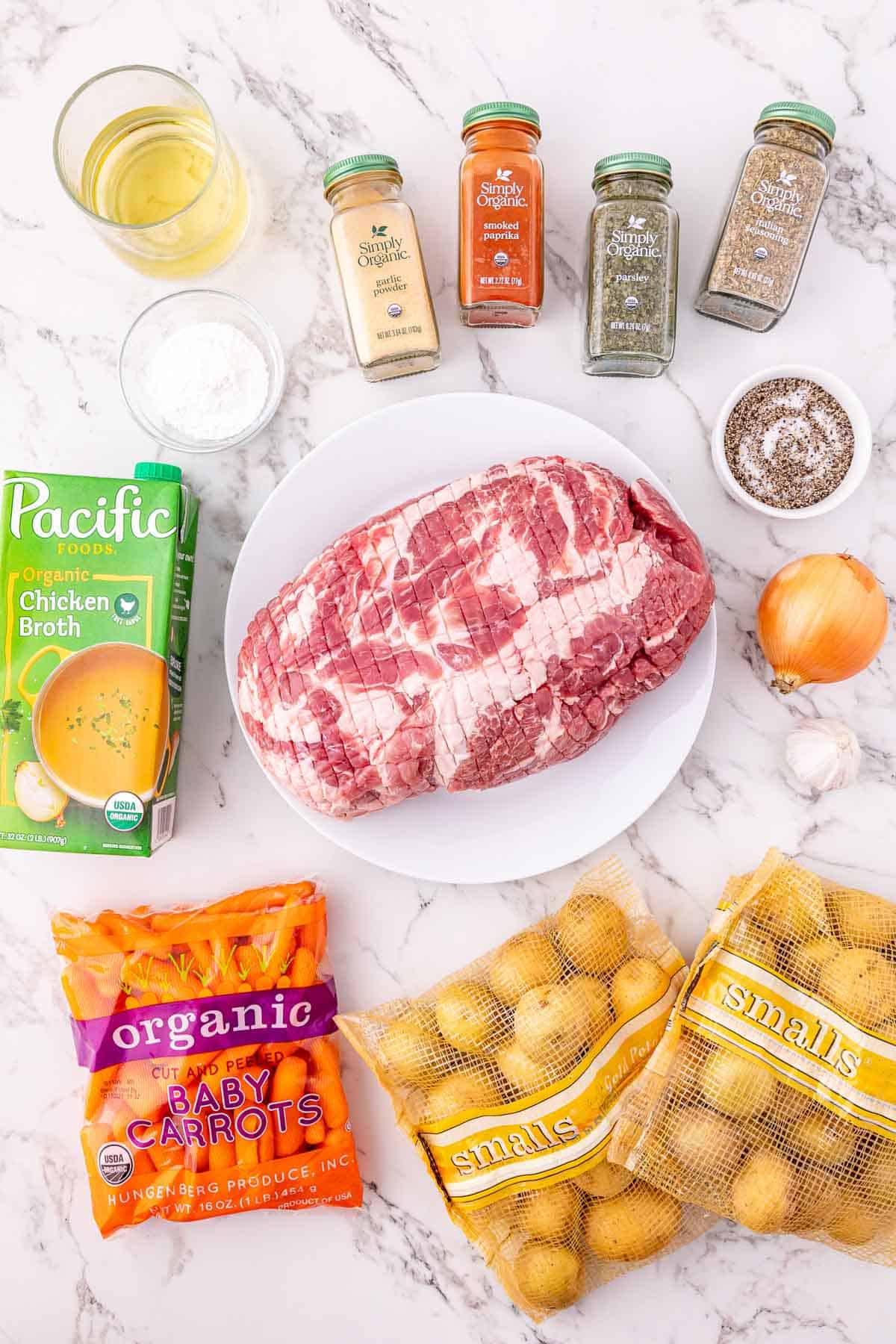 Ingredients for a Crock Pot Pork Roast, including raw meat, potatoes, carrots, onion, seasonings, and chicken broth. Perfect for a hearty and flavorful slow-cooked meal.