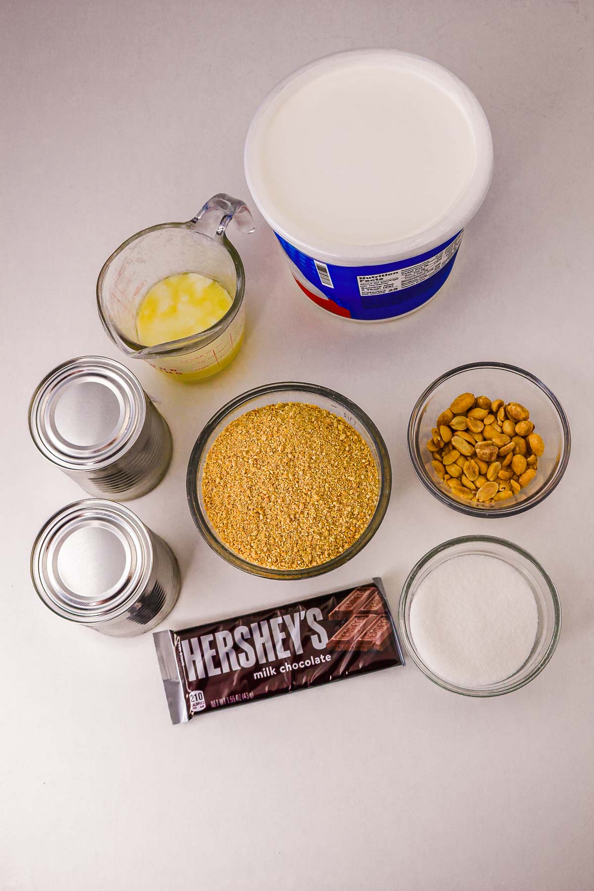 Top view of baking ingredients for a delicious Caramel Pie: whipped topping, peanuts, sugar, butter, sweetened milk, graham crumbs, and chocolate—perfect for your next slow cooker recipe.