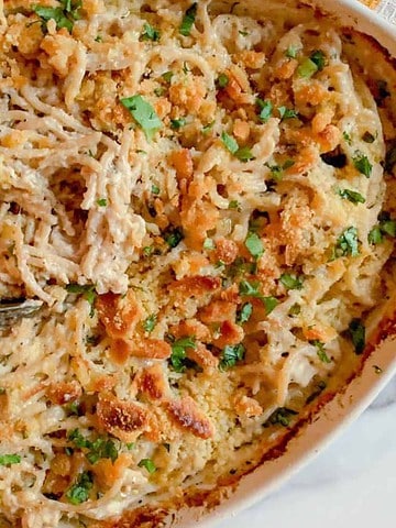 Baked chicken spaghetti casserole with golden breadcrumb topping in a white dish, served with a spoon—a comforting nod to vintage casseroles perfect for any family reunion.