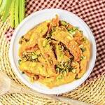 Plate of dumplings topped with sesame seeds and chopped green onions on a woven placemat and checkered cloth—perfect for trying out that viral dumpling recipe from TikTok!.