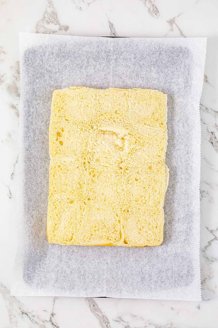 A large, sliced yellow sponge cake on parchment paper atop a marble surface—perfect for serving alongside Easy BBQ Chicken or tasty BBQ Chicken Sliders at your next gathering.
