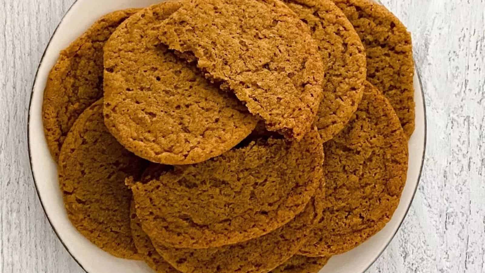 A plate of brown, crispy cookies, with one cookie partially broken on top.