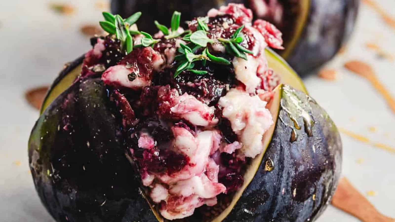 A close-up of a fig stuffed with creamy cheese, berries, and garnished with fresh thyme.