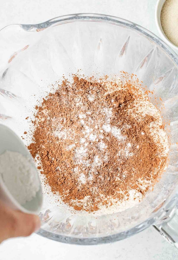 A glass bowl with flour, cocoa powder, and baking powder being mixed for a delicious Hot Chocolate Cobbler dessert.