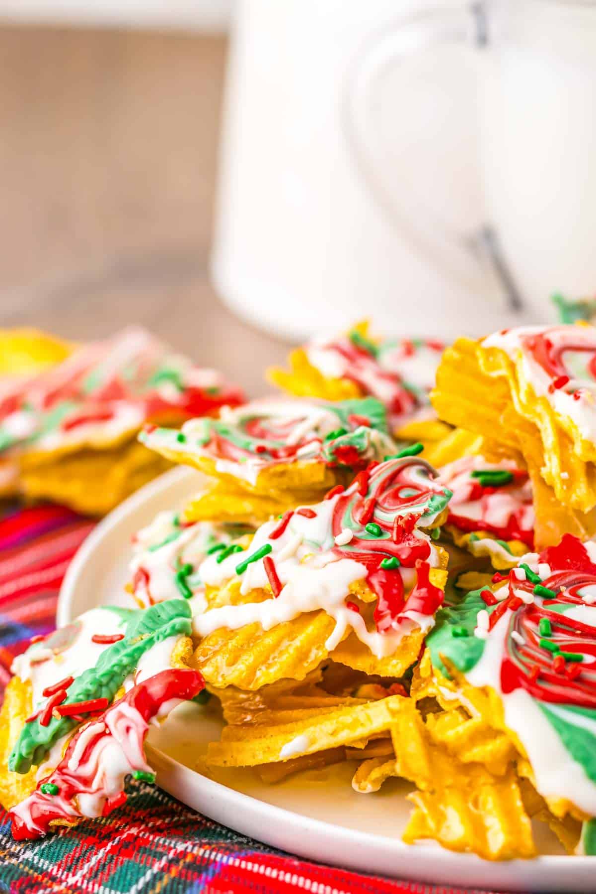 Potato Chip Christmas Crack recipe: Potato chips covered in white chocolate with red and green sprinkles on a plate, festive for the holidays.