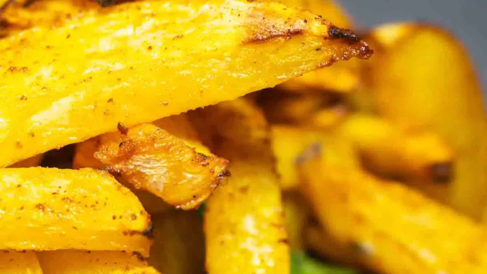 Close-up of golden, seasoned potato wedges with a crispy texture and visible char marks.