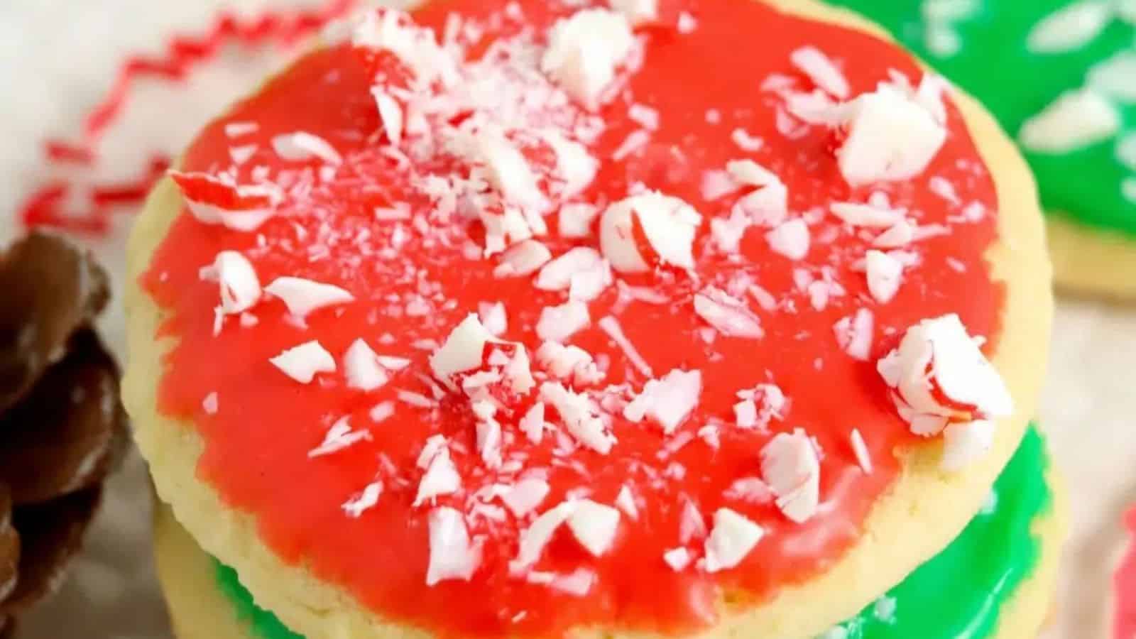 A sugar cookie with red icing and crushed peppermint candy sprinkled on top.
