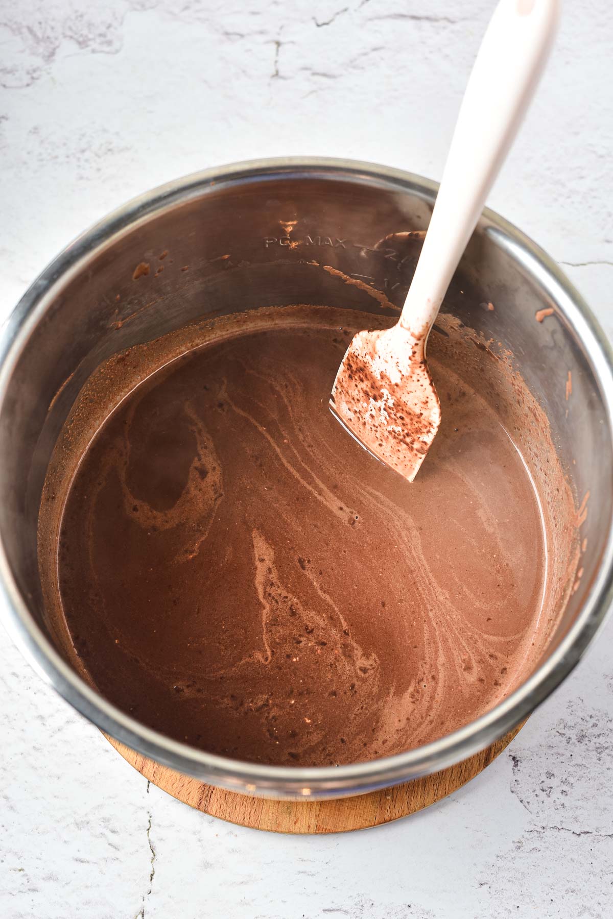 A mixing bowl with chocolate batter and a white spatula on a light countertop, perfect for creating Peppermint Hot Chocolate treats.