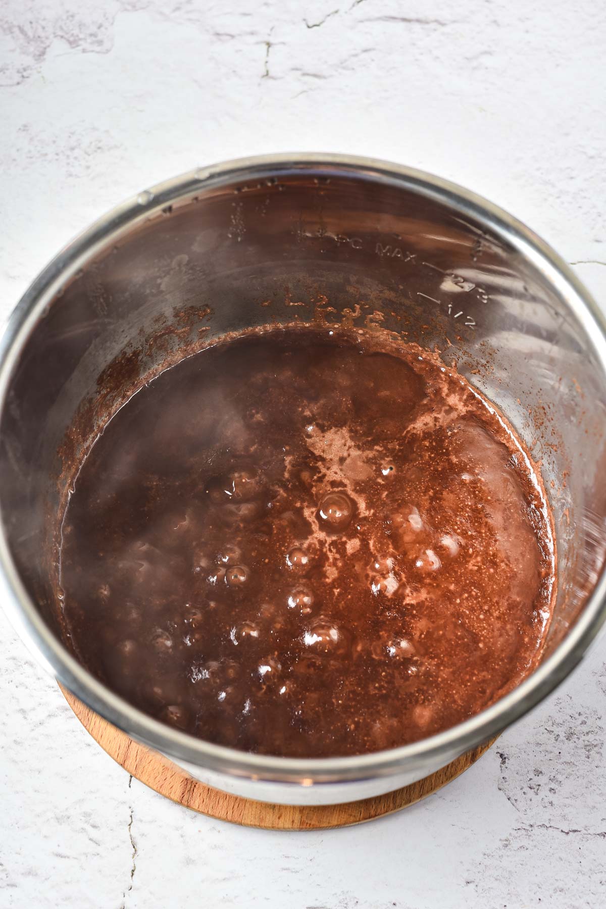 Peppermint Hot Chocolate mixture boiling in a stainless steel pot on a light textured surface.
